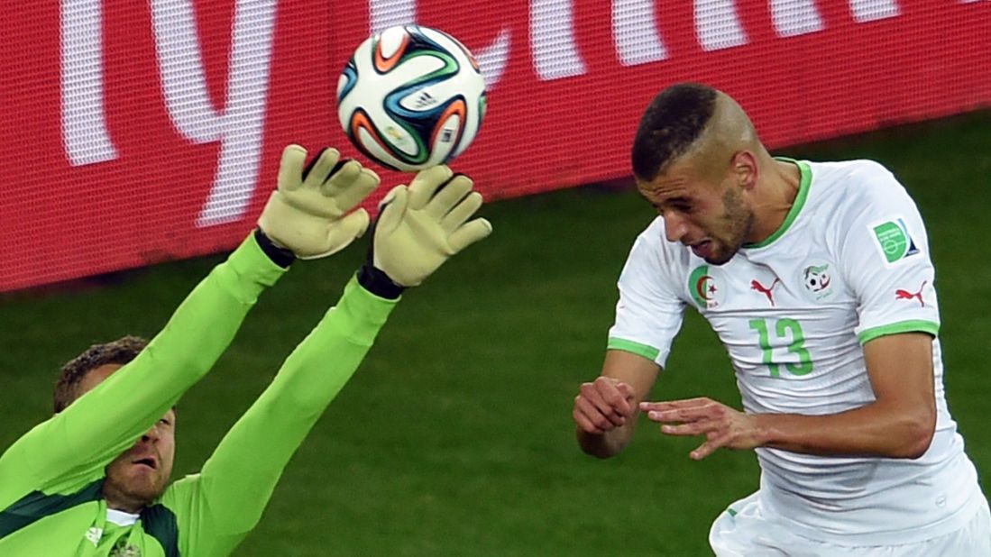 Algeria forward Islam Slimani, right,  heads the ball to score a goal past Russia's goalkeeper Igor Akinfeev during a World Cup match at the Baixada Arena in Curitiba, Brazil. 