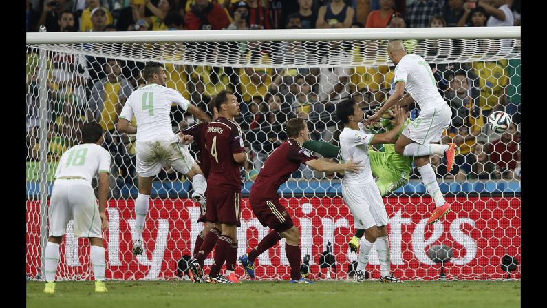 Algeria forward Islam Slimani, right, scores his team's first goal past Russia's goalkeeper Igor Akinfeev.