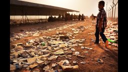 A child walks over discarded water bottles and trash at a registration area at the displacement camp in Khazair on June 26.