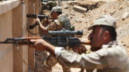 Kurdish Peshmerga fighters take their positions behind a wall on the front line of the conflict with ISIS militants in Tuz Khormato, Iraq, on Wednesday, June 25.