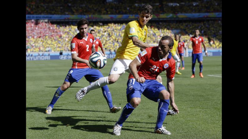 Brazil's Oscar, center, is challenged by Chile's Marcelo Diaz, right, on June 26.