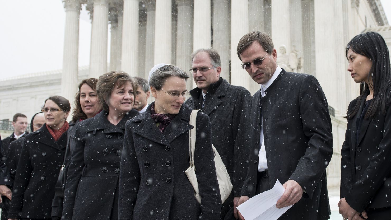 Carolyn Hahn, center, watches as husband Anthony prepares to talk to reporters outside the U.S. Supreme Court on March 25.