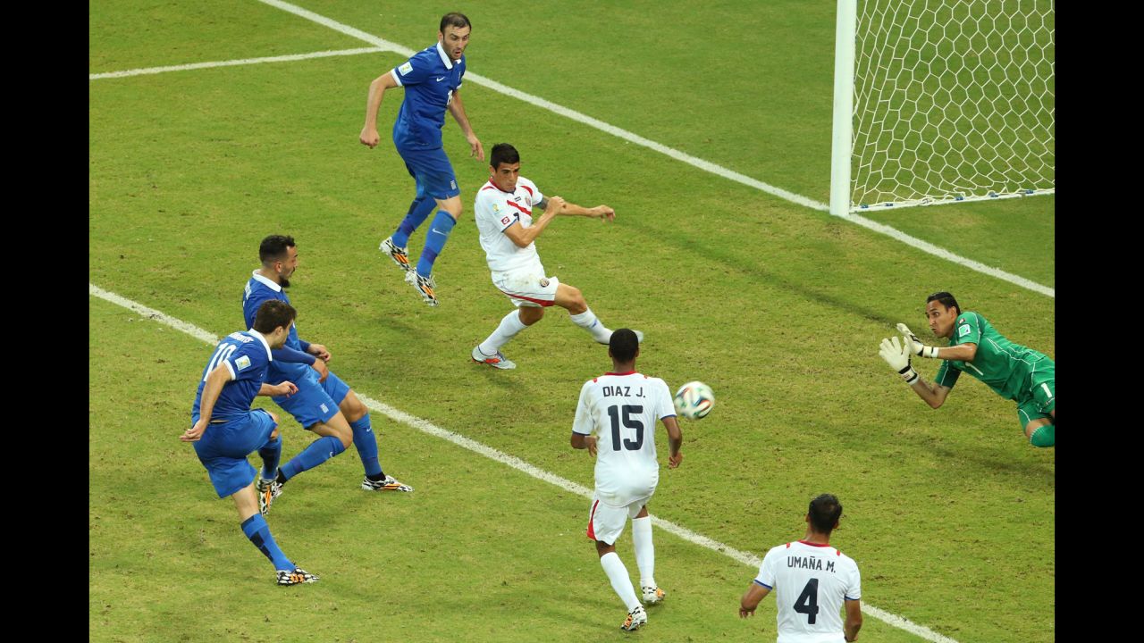 Sokratis Papastathopoulos of Greece, left, shoots and scores late in the second half to tie Costa Rica during a game in Recife, Brazil, on Sunday, June 29. The elimination-round game ended with a final score of 1-1. Costa Rica advanced by winning a penalty kick shootout.