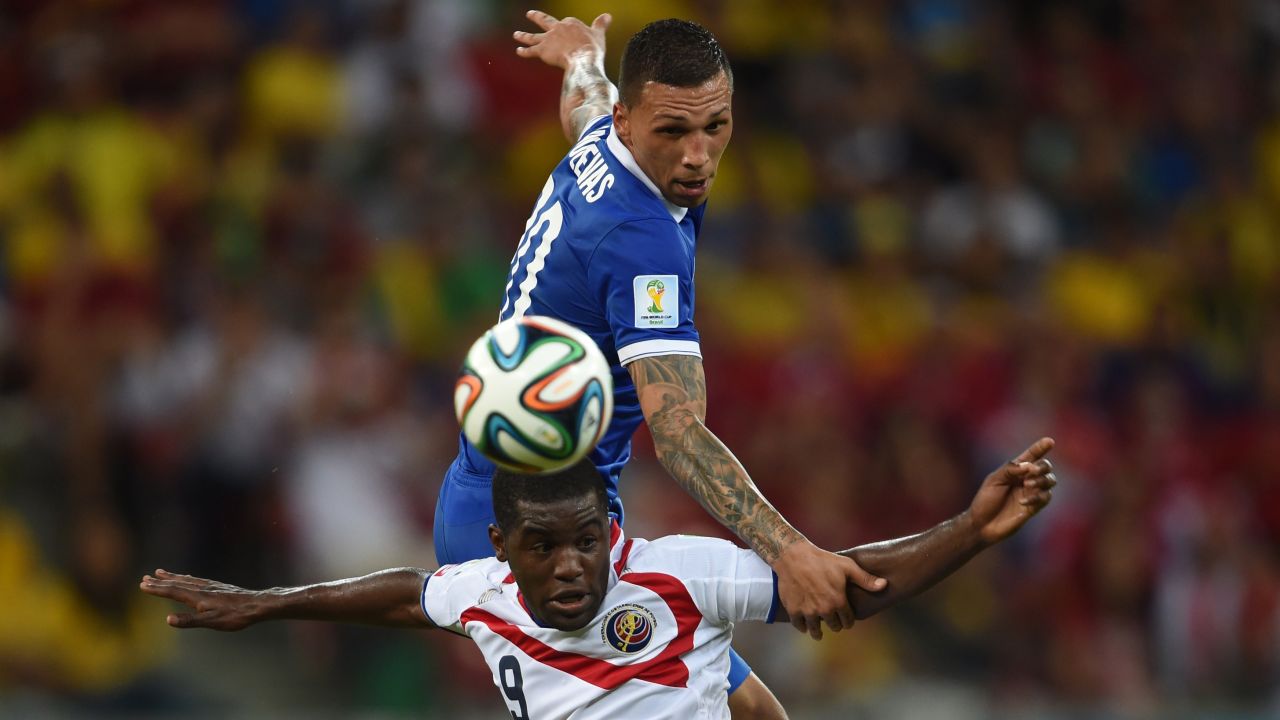 Greece's Jose Holebas jumps over Costa Rica's Joel Campbell.