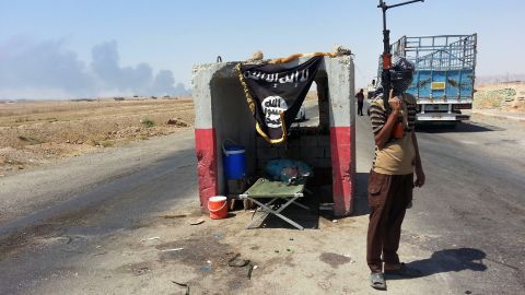 An ISIS militant stands guard at a checkpoint captured from the Iraqi Army outside Beiji refinery on June 19, 2014.
