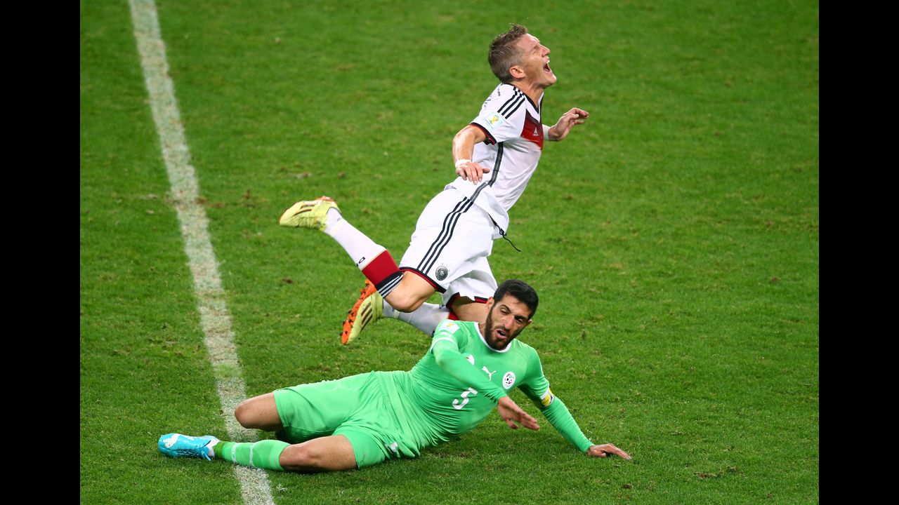 Algerian defender Rafik Halliche slides under Germany's Bastian Schweinsteiger. Halliche received a yellow card for the challenge.