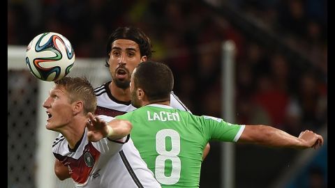 Germany's Bastian Schweinsteiger, left, and Sami Khedira fight for the ball with Algeria midfielder Medhi Lacen.