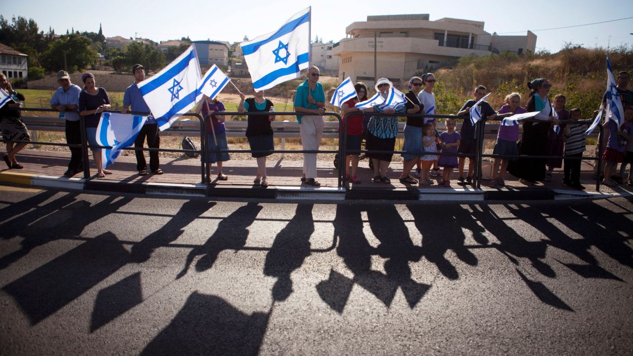 People hold Israeli flags during Shaar's funeral procession in Hashmonaim, West Bank.