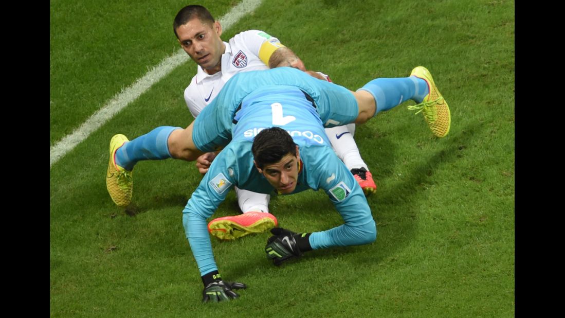 Belgium's goalkeeper, Thibaut Courtois, falls on U.S. forward Clint Dempsey.