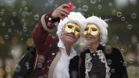 Guests dressed in period costumes pose for a selfie Saturday, June 28, at a ball held in the gardens of the Palace of Versailles in Versailles, France.