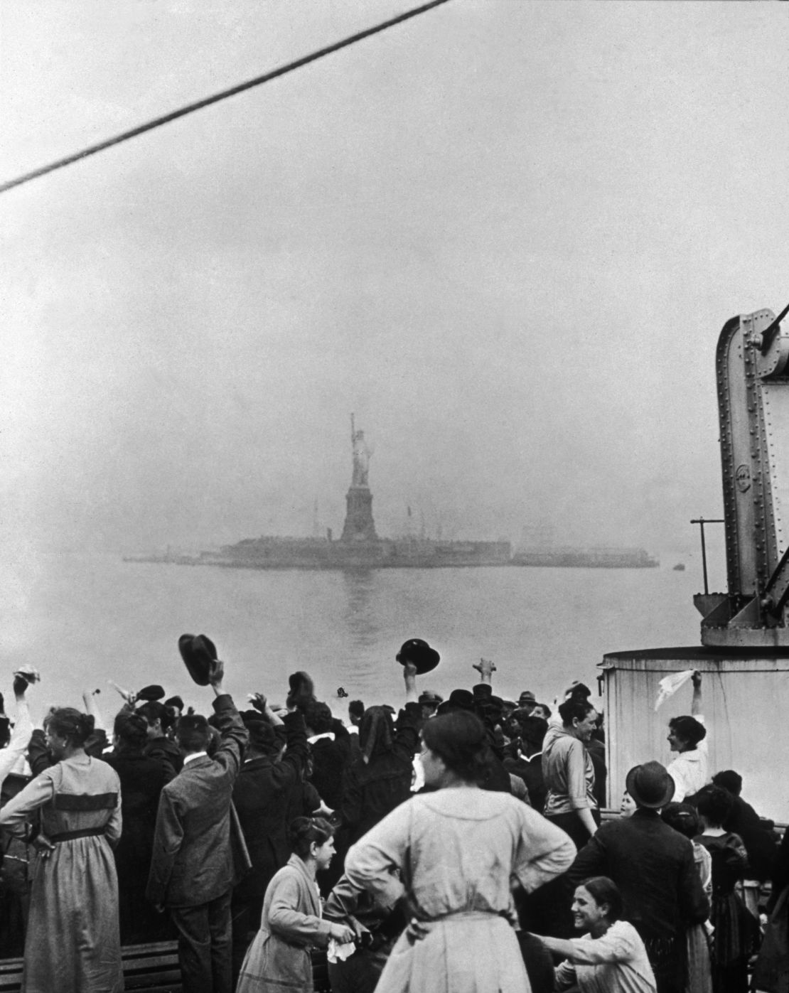 Immigrants traveling aboard a ship celebrate as they catch their first glimpse of the Statue of Liberty and Ellis Island in New York Harbor in 1915. 
