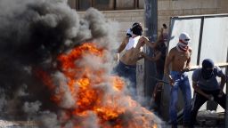 Masked Palestinian protesters throw stones towards Israeli police (unseen) during clashes in the Shuafat neighborhood in Jerusalem, on July 2, 2014.