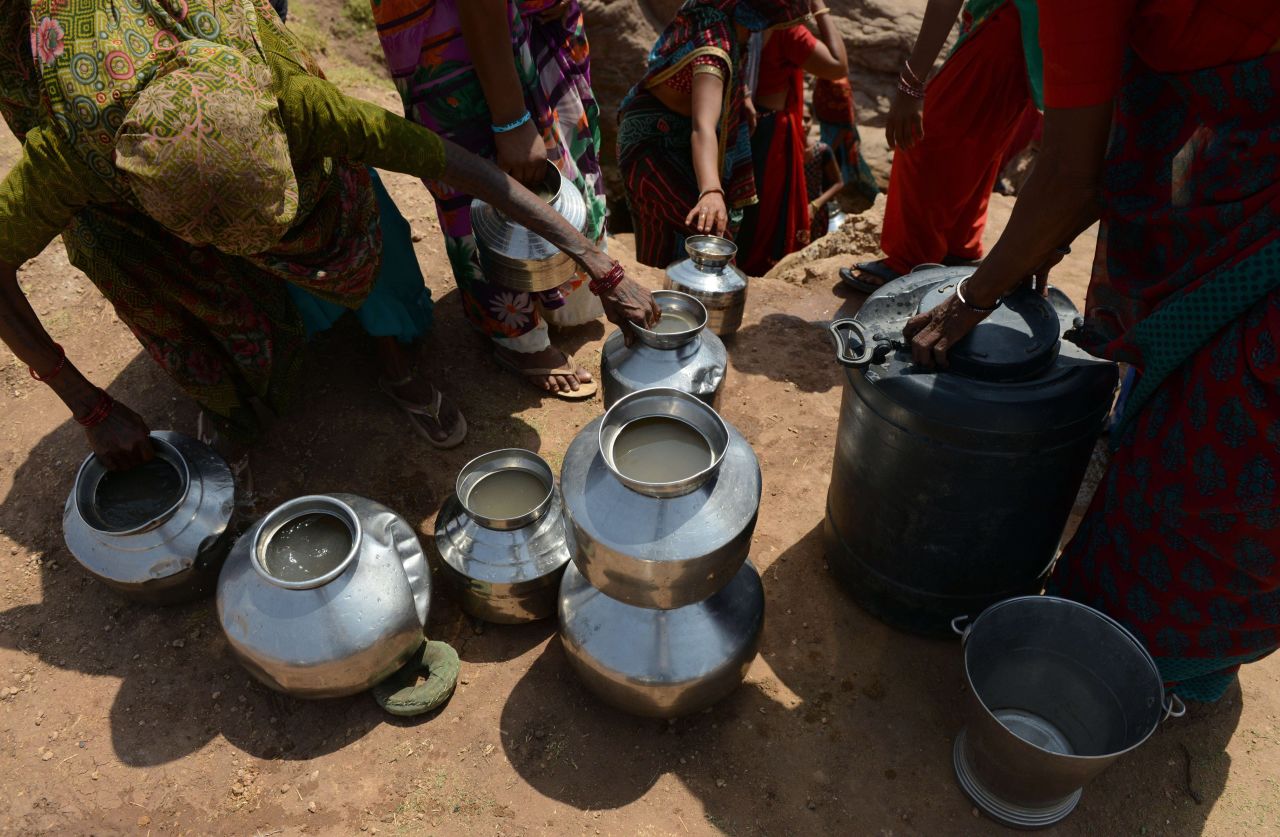 Villagers in Surendranagar, India, use pots to collect drinking water from a man-made well on June 1.