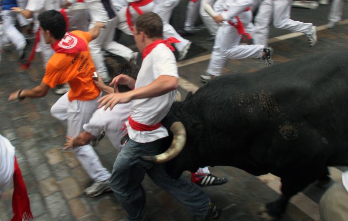A young man is caught between the bull's horns as he is tossed on July 8, 2007 in the old city streets of Pamplona. Thousands of "runners" test their skill, courage, and luck in the 900-meter course made famous by Ernest Hemingway's 1926 novel "The Sun Also Rises," first published in 1926. The man was thrown against a fence but not injured. These images by photographer Jim Hollander appear in a new book "<a href="index.php?page=&url=http%3A%2F%2Fwww.thebullsofpamplona.com" target="_blank" target="_blank">Fiesta: How To Survive The Bulls Of Pamplona</a>."