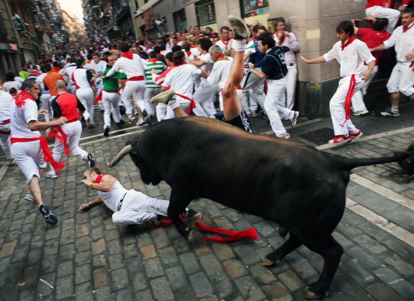 One runner tries to protect himself from a fighting bull from the Fuente Ymbro ranch as another is upside-down with both feet in the air during the third "encierro," or Running of the Bulls in Pamplona's Fiesta de San Fermin on July 9, 2008.