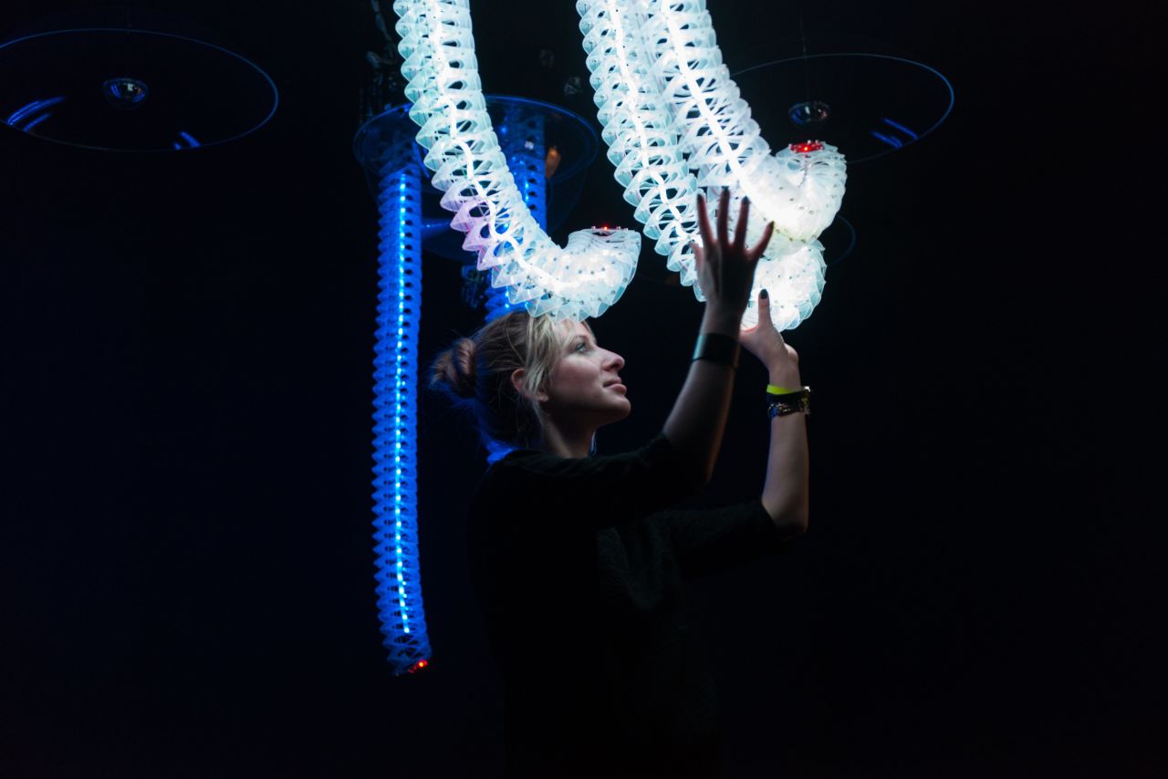 A girl plays with responsive snake-like robotic arms in interactive sculpture "Petting Zoo" by Minimaforms.