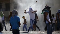 A masked Palestinian protester uses a slingshot to throw stones towards Israeli police (unseen) during clashes in the Shuafat neighborhood in Israeli-annexed Arab East Jerusalem, on July 3, 2014.