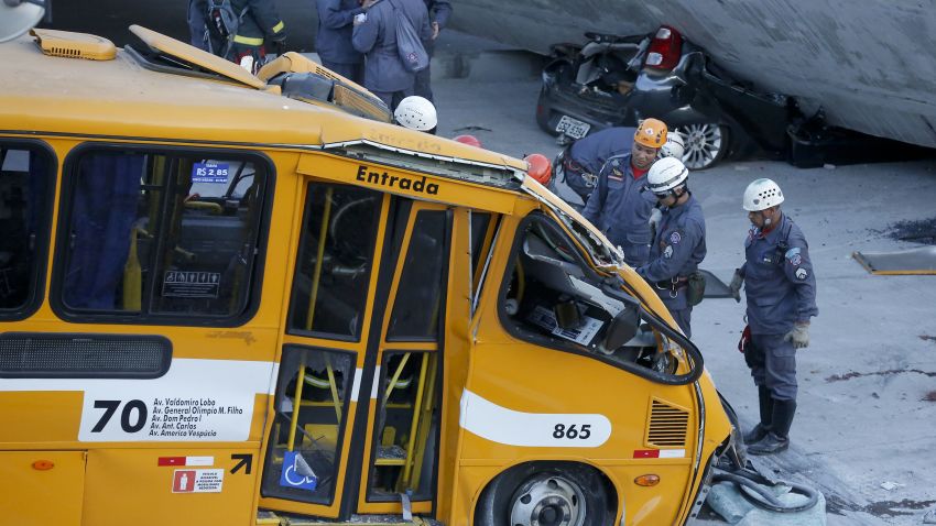 Fire department personnel work to retrieve a body from a bus after retrieving it from underneath a collapsed bridge in Belo Horizonte, Brazil, Thursday, July 3, 2014. The overpass under construction collapsed Thursday in the Brazilian World Cup host city. The incident took place on a main avenue, the expansion of which was part of the World Cup infrastructure plan but, like most urban MOBILITY projects related to the Cup, was not finished on time for the event. (AP Photo/Victor R. Caivano)