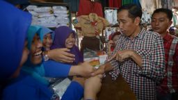 Indonesian vendors shake hands with presidential candidate Joko Widodo as he visits a traditional market during his campaign in Jakarta on June 30.