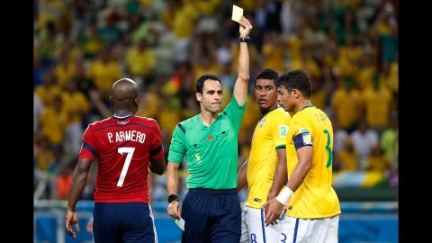 Brazil's Thiago Silva, right, receives a yellow card from referee Carlos Velasco Carballo.