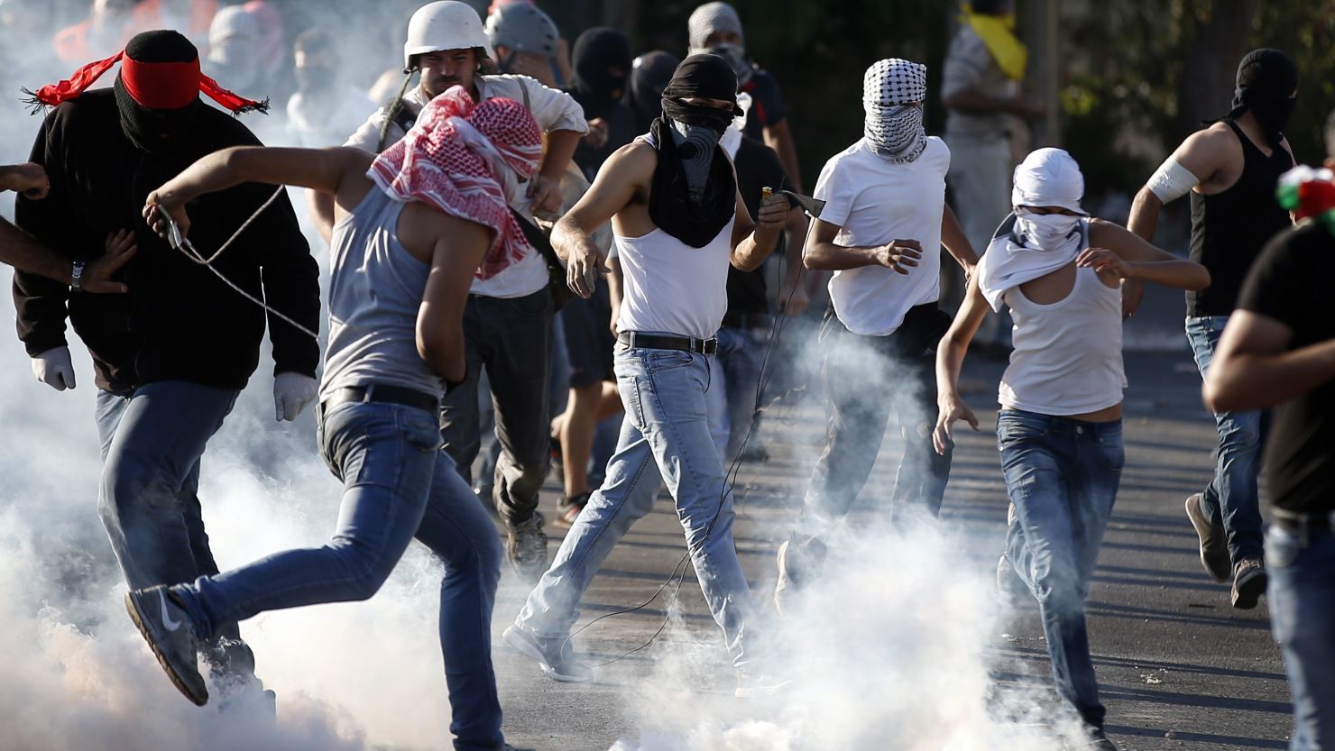 Palestinian protesters stand amid smoke after Israeli forces fired tear gas in East Jerusalem on July 4.
