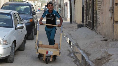 Mustafa, 15, pushes a trolley he uses in his day job transferring goods across the area to help support his family.