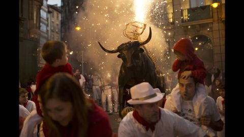 Revelers run away from a flaming fake bull during the second day of the festival on Monday, July 7.