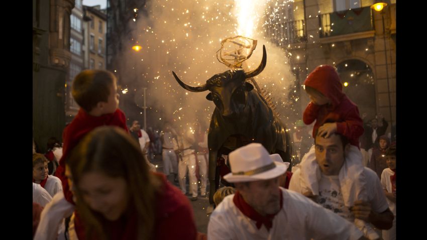 Revelers run away followed by a flaming fake bull "Toro de fuego" during the second  day of the 2014 San Fermin fiestas in Pamplona, Spain, Monday, July 7, 2014. Revelers from around the world arrive to Pamplona every year to take part on some of the eight days of the running of the bulls glorified by Ernest Hemingway's 1926 novel "The Sun Also Rises."  (AP Photo/Andres Kudacki)