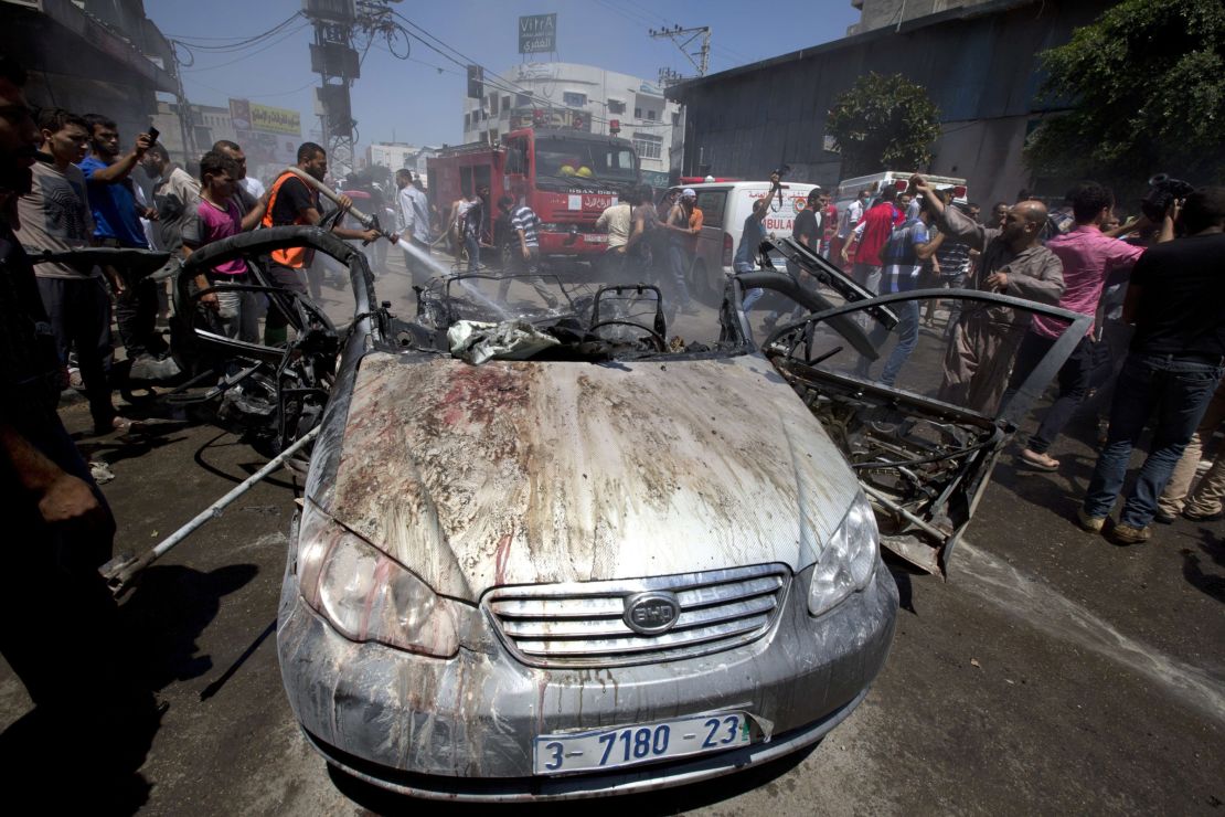 Firefighters extinguish a vehicle targeted in an Israeli airstrike on Gaza City on July 8, 2014. 