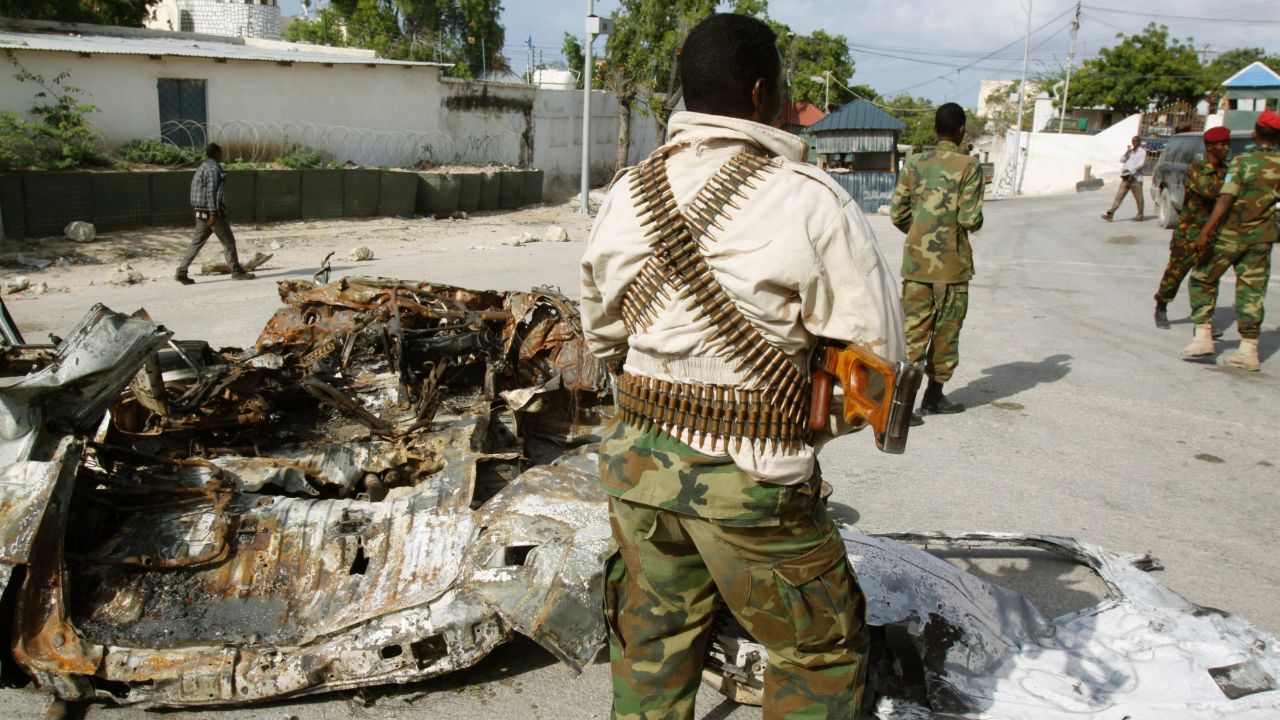Soldiers stand near the wreckage of a car bomb in Mogadishu, Somalia, on July, 9, 2014.