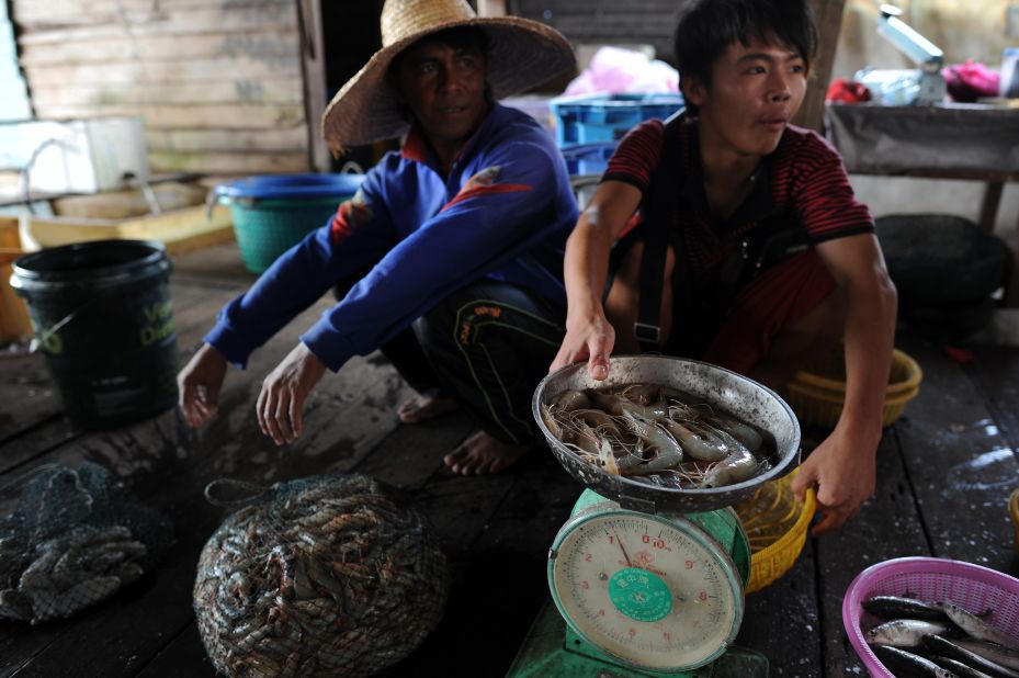 About 1 billion people, mainly in developing countries, rely on fish as their primary animal protein source. This photo shows workers at a wholesale market in Tanjung Karang, a fishing village in Malaysia.