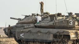 Israeli soldiers stand on Merkava tanks in an army deployment area near Israel's border with Gaza on July 9, 2014.
