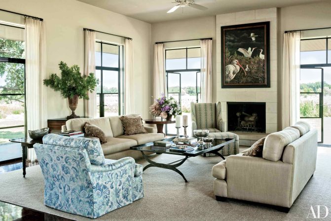 Living Room: Mounted on the living area's limestone chimney breast is an Adrian Martinez painting, which over looks sofas clad in a Glant fabric, a club chair upholstered in a Groves Bros. print, and a cocktail table designed by Mrs. Bush; the windows are curtained in a Calvin Fabrics linen, and the ammonite fossils displayed atop the pedestal table were found on the property. <a href="index.php?page=&url=http%3A%2F%2Fwww.architecturaldigest.com%2Fcelebrity-homes%2F2014%2Flaura-and-george-w-bush-prairie-chapel-ranch-texas-article%3Fmbid%3Dsynd_cnn" target="_blank" target="_blank">See more at ArchDigest.com</a>