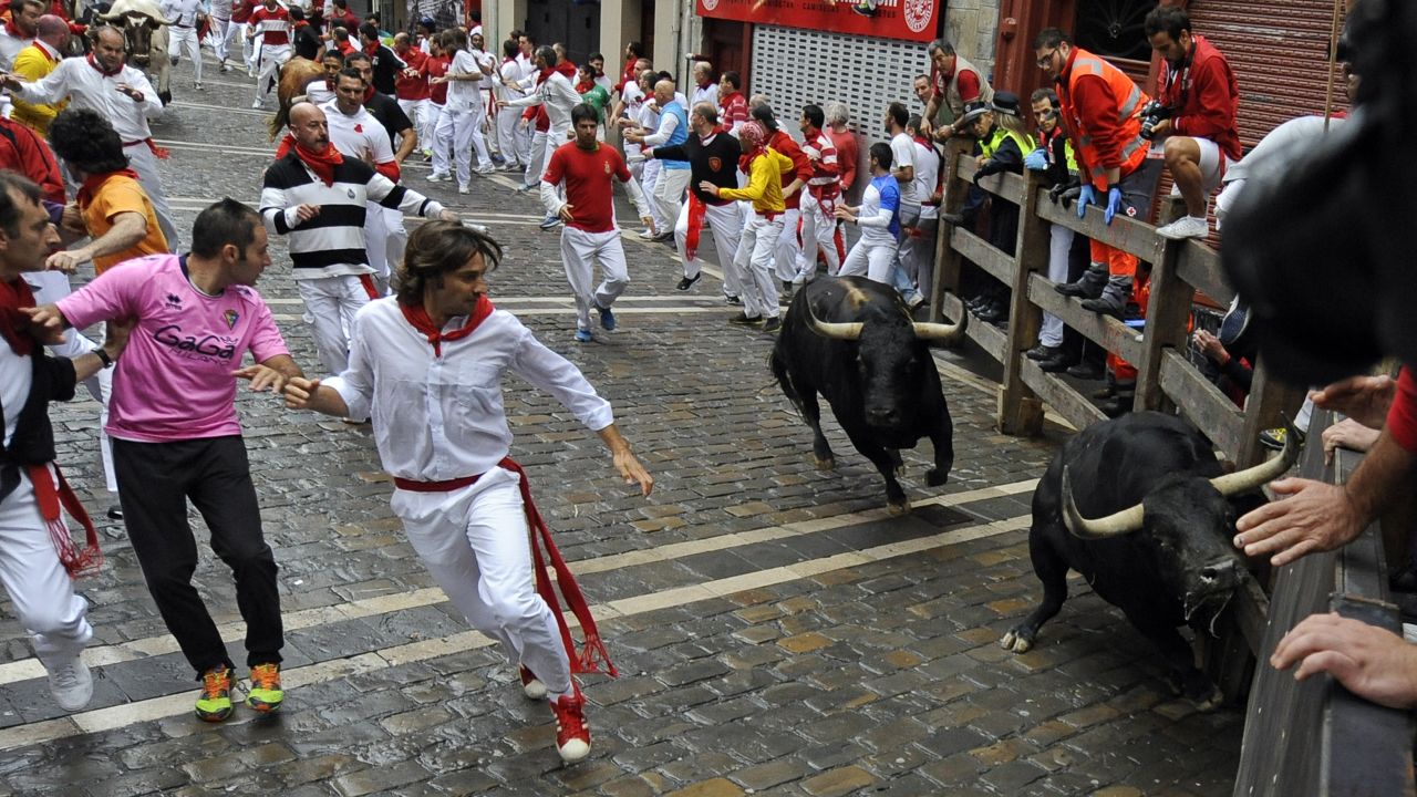 Participants run in front of Victoriano del Rio Cortes' bulls during the third bull-run of the San Fermin Festival in Pamplona, northern Spain, on July 9, 2014. The festival is a symbol of Spanish culture that attracts thousands of tourists to watch the bull runs despite heavy condemnation from animal rights groups. AFP PHOTO / RAFA RIVAS        (Photo credit should read RAFA RIVAS/AFP/Getty Images)