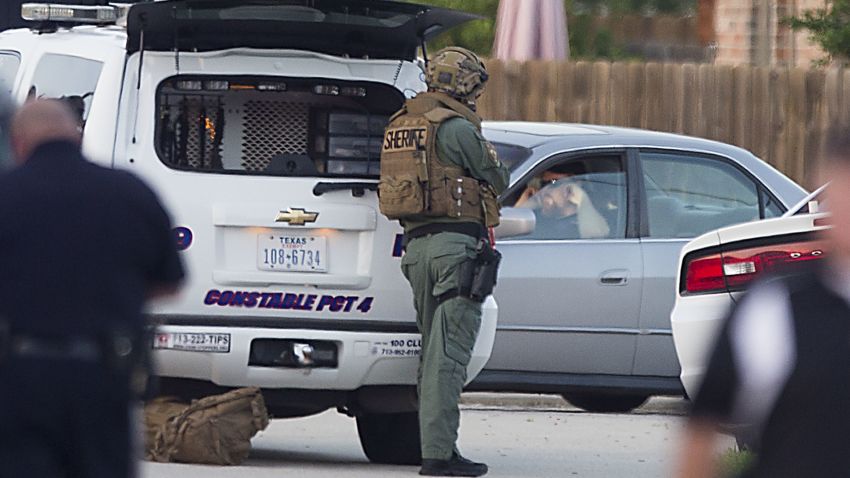 Law enforcement officers surround a shooting suspect in his car Wednesday, July 9, 2014, in Spring, Texas. Deputies cornered the suspect in a shooting at a suburban Houston home that resulted in multiple fatalities. (AP Photo/Houston Chronicle, Brett Coomer)