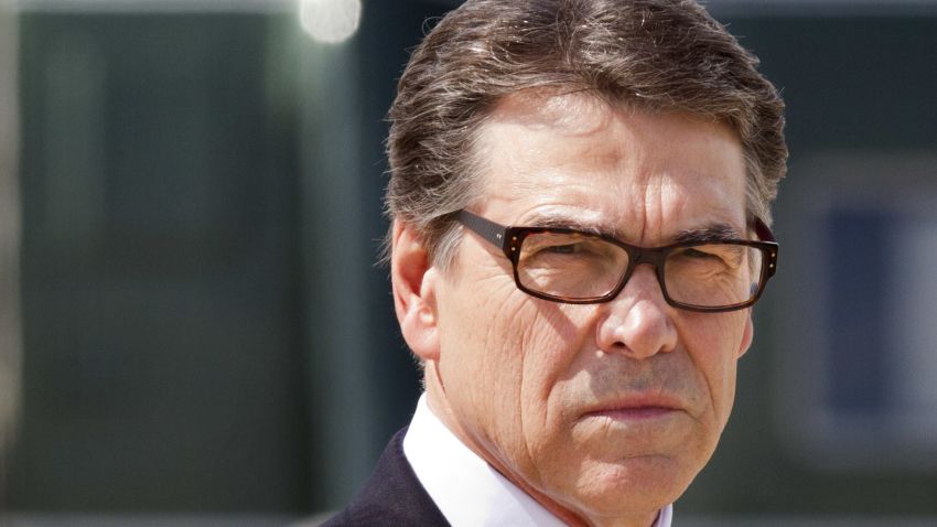 Texas Gov. Rick Perry waits to meet President Barack Obama on arrival in Dallas where they will attend a meeting on immigration, Wednesday, July 9, 2014. (AP Photo/Jacquelyn Martin)
