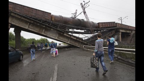 People walk under a destroyed railroad bridge near the village of Novobakhmutivka on Monday, July 7.