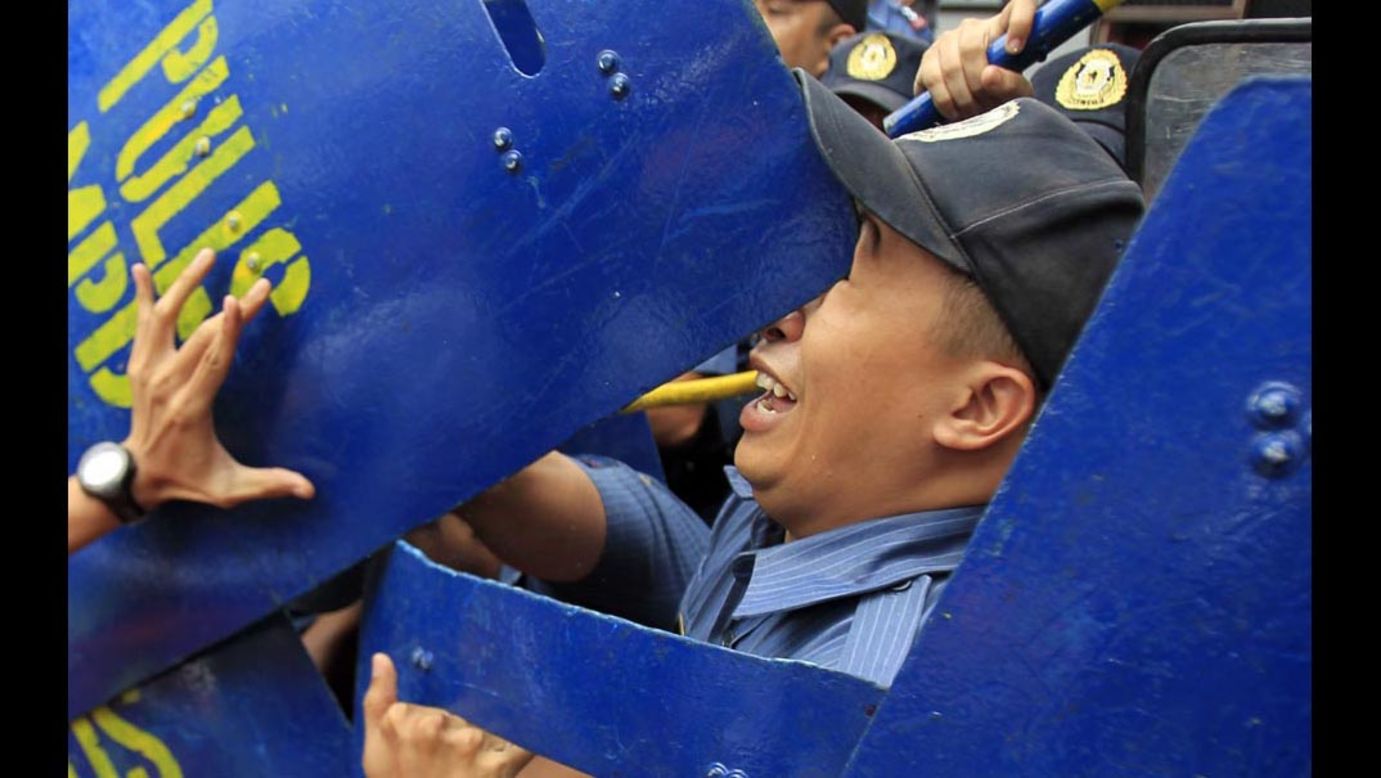 An anti-riot policeman is hit in the face with a colleague's shield after a protester, left, pushed away the shield during a demonstration held Friday, July 4, outside the U.S. Embassy in Manila, Philippines. The protesters commemorated Filipino-American Friendship Day with a rally demanding the pullout of U.S. troops in the Philippines.