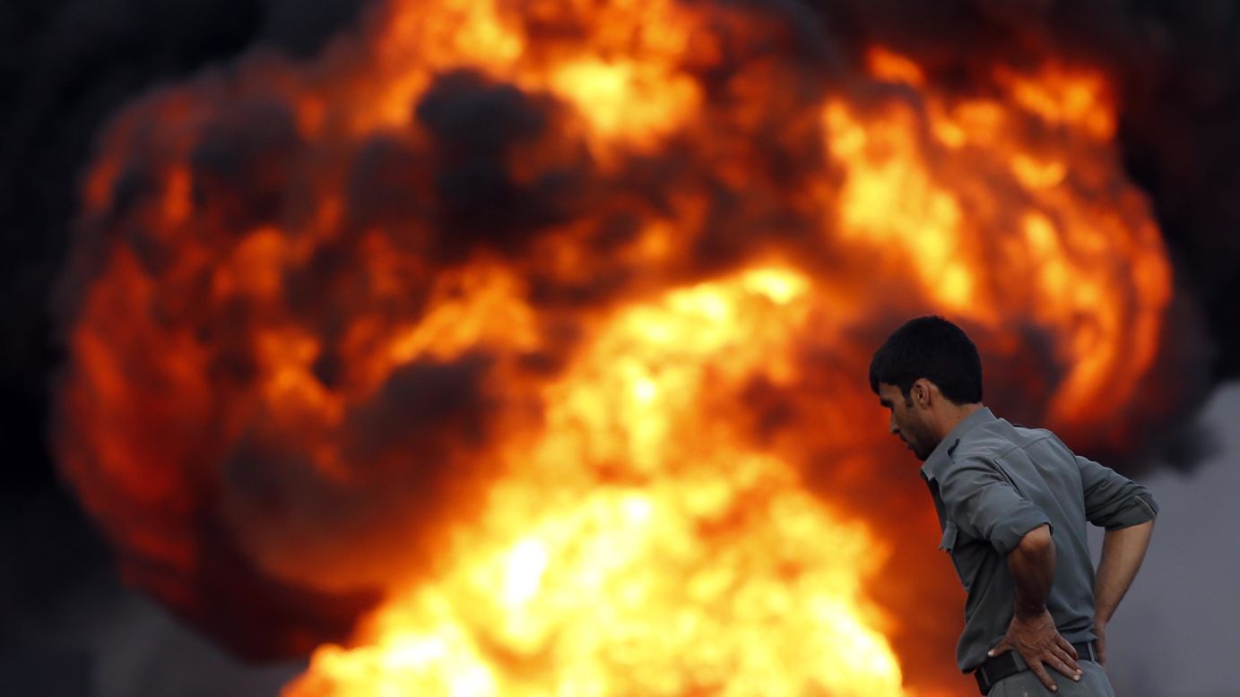 An Afghan policeman looks at a fire after <a href="http://www.cnn.com/2014/07/05/world/asia/afghanistan-truck-fires/index.html">an overnight attack by the Taliban</a> on Saturday, July 5. More than 400 trucks carrying fuel and oil were burning on roads west of Kabul, Afghanistan, police spokesman Hashmatullah Stanekzai said. The Taliban claimed in a statement that their fighters had attacked a parking depot used by trucks delivering supplies to NATO.