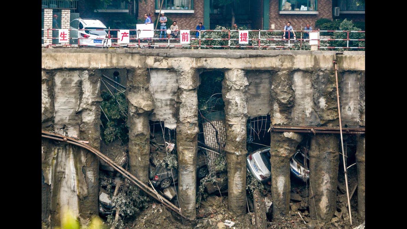 Cars are seen in a sunken parking lot after heavy rainfall hit Chengdu, China, on Wednesday, July 9. When the ground gave way, four cars fell into the pit and one was left stuck on the edge of a railing, according to local media.