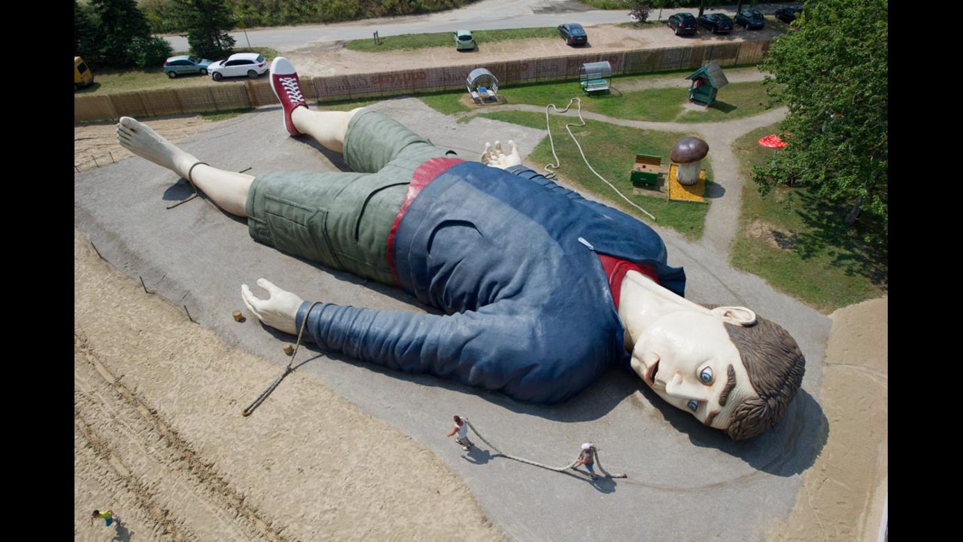 Workers carry a rope next to a sculpture of the literary character Gulliver at the Gulliver's World amusement park in Usedom, Germany, on Tuesday, July 8. The sculpture is 36 meters (118 feet) long.
