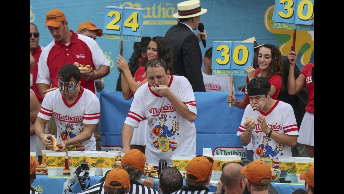 From left, competitive eaters Tim Janus, Joey Chestnut and Matt Stonie wolf down hot dogs Friday, July 4, during the 98th annual <a href="http://www.cnn.com/2014/07/04/us/gallery/coney-hot-dog/index.html">Nathan's Famous Hot Dog Eating Contest</a> at Coney Island in New York. Chestnut ate 61 hot dogs to win the men's competition for the eighth straight year.