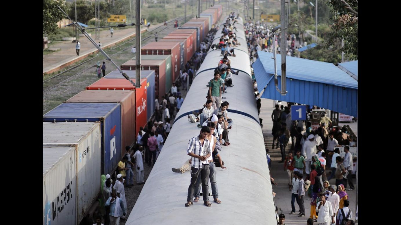 Passengers ride on the top of an overcrowded train in Loni, India, on Monday, July 7.