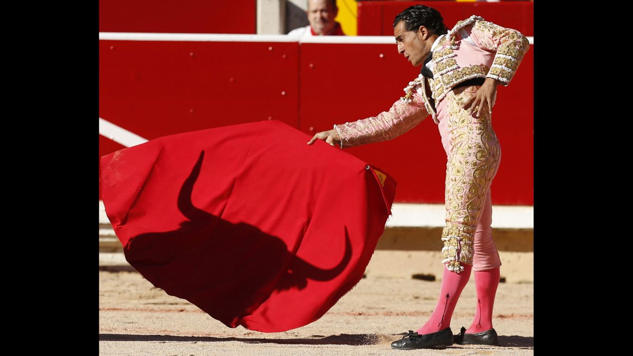The shadow of a bull falls on the cape of bullfighter Ivan Fandino on Wednesday, July 9. Each day's run ends in the bull ring.