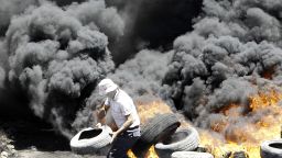 A Palestinian burns tires during clashes with Israeli security forces following a protest near the northern city of Nablus, in the occupied West Bank on July 11, 2014.