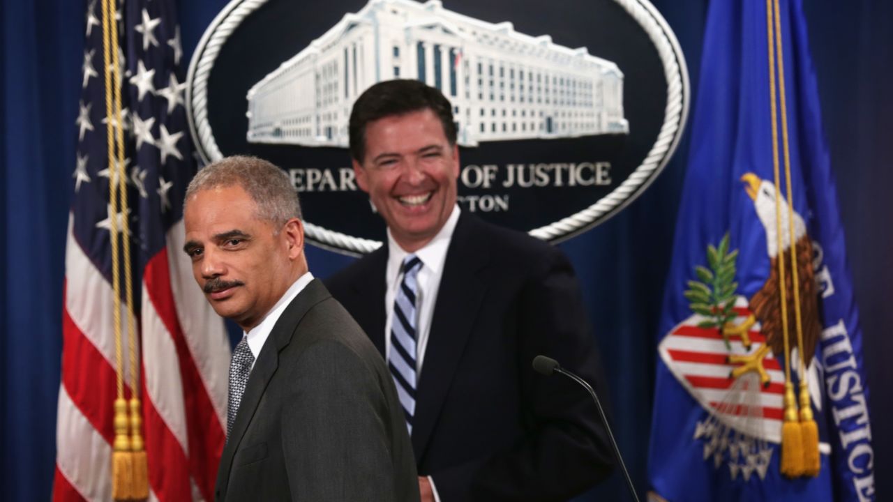 Attorney General Eric Holder (L) and FBI Director James Comey (R) leave after a major law enforcement action announcement at the Justice Department June 30, 2014 in Washington.