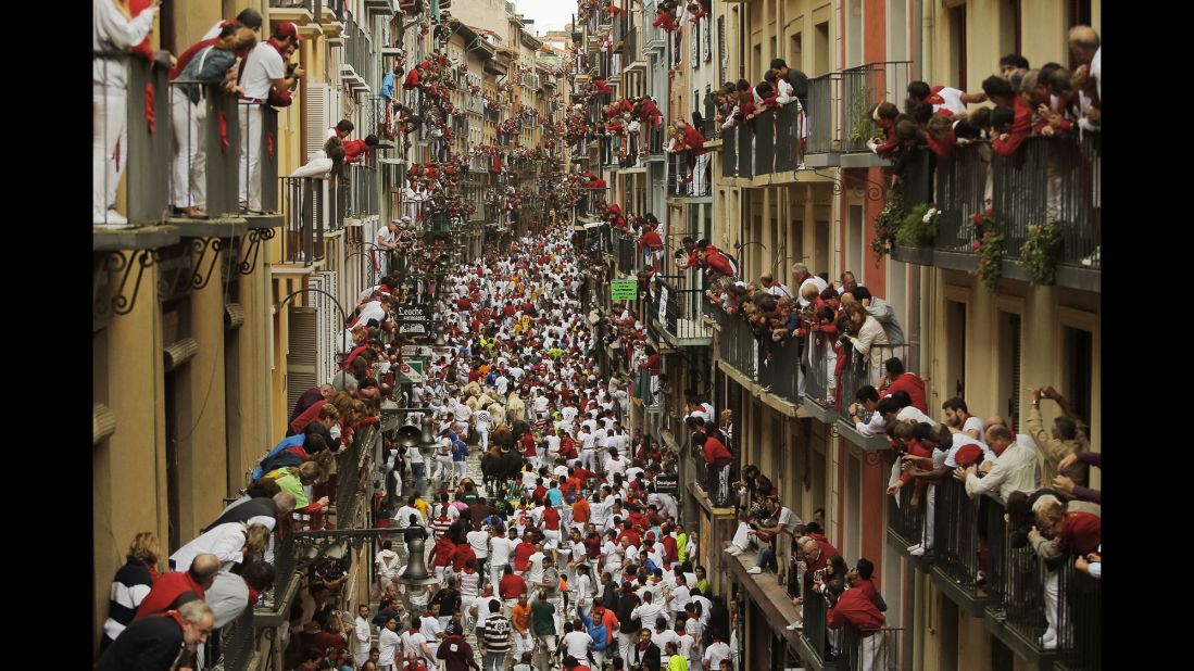 People watch as revelers and bulls fill a street on July 12. 