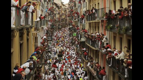 People watch as revelers and bulls fill a street on July 12. 