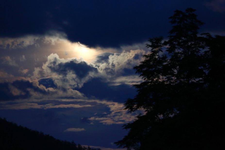 The moon casts a glow on clouds over a forest near Sarajevo.