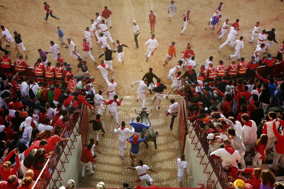 Revelers and bulls run as they enter the bullring on July 13. 